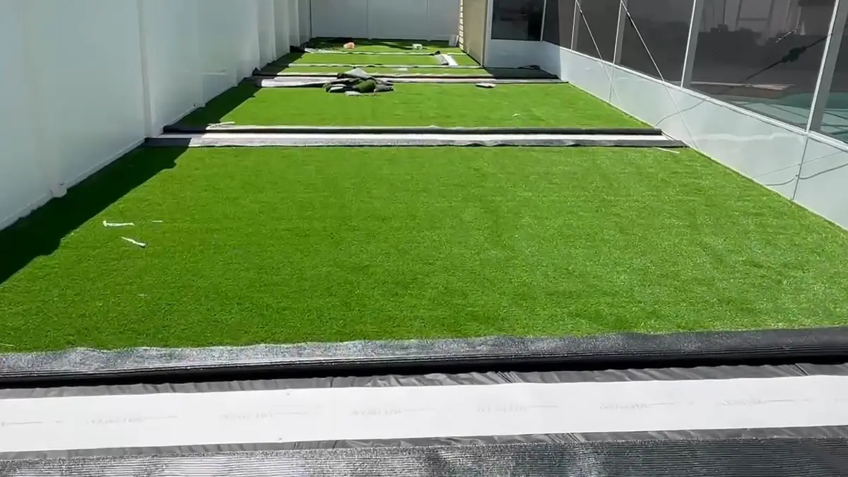 Artificial turf being installed next to a pool screen enclosure
