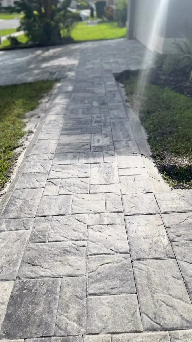Gray paver side walkway between a home and landscaping