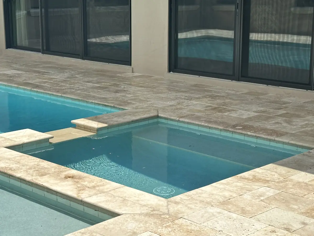 Travertine pool deck around a pool and spa